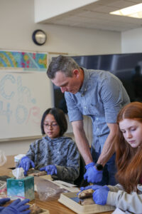 Teacher assisting two students in a science lab