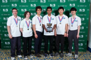 team posing with trophy in front of national science bowl backgrop