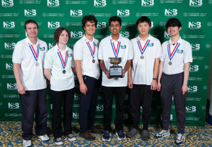 team posing with trophy in front of national science bowl backgrop